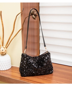 Detail of black sequined shoulder bag with elegant golden metal hooks on wooden surface