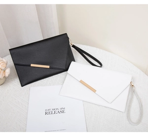 Dettaglio di eleganti pochette a busta con finiture in metallo dorato in nero e bianco