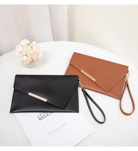 Dettaglio di eleganti pochette a busta in pelle nera e marrone con finiture dorate