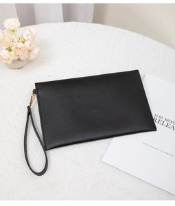 Dettaglio pochette a busta in pelle nera con finiture dorate e cinturino da polso