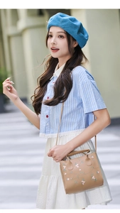 Outdoor shot of a light brown mini handbag with pink floral embroidery and crossbody strap