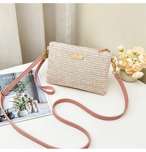 Detail view of beige woven crossbody bag with pink leather strap and gold hardware