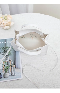 Detail view of the white leather tote bag interior with floral lining and zipper pocket