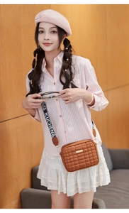 Brown quilted crossbody bag featuring a wide patterned strap on a stylish outfit