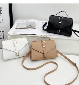Detailed view of three minimalist square bags in black, white, and khaki textured PU leather