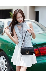Fashionable black shoulder bag with a gold horseshoe buckle styled on a model outdoors