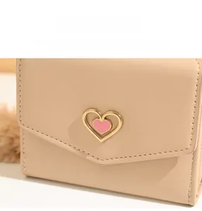 Close-up of beige leather wallet with heart-shaped gold buckle and white stitching details
