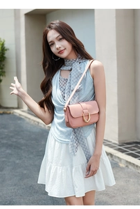 Detail of pink matte leather crossbody bag with golden horseshoe buckle worn by a model