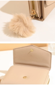Detail of beige PU leather wallet with plush pompom charm and golden hardware