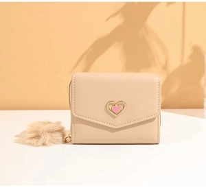 Detail of beige trifold wallet with golden heart clasp and soft pompom charm accessory