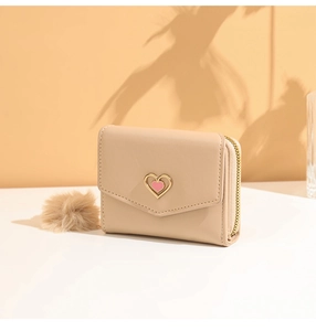 Close-up of beige heart mini wallet with gold heart metal charm and soft fur ball pendant