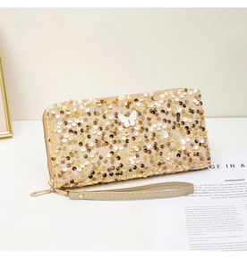 Detailed view of long gold sequin clutch with butterfly ornament and metallic wrist strap