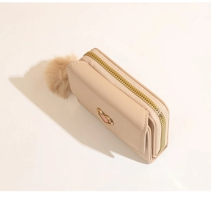 Detail of beige leather wallet with heart metal buckle and soft plush ball pendant charm