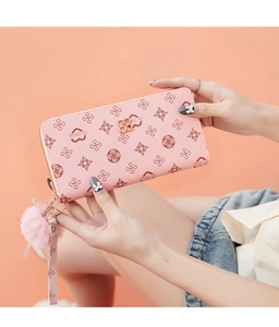 Pink faux leather clutch with heart pattern, gold clover logo and fluffy pompom detail