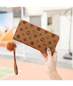 Detail of brown faux leather long wallet with floral print and pompom decorative keychain