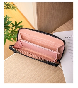 Dettaglio di un portafoglio lungo nero con interno rosa multi-slot su sfondo in legno