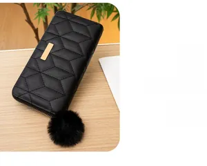 Dettaglio di un portafoglio trapuntato nero con elegante cerniera a pompon in pelo