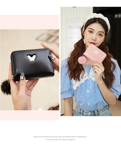 Close-up of patent leather butterfly wallets in pink and black with fluffy pompom charm