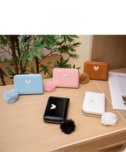 Detailed view of glossy oil leather wallets with butterfly logo and plush ball charms