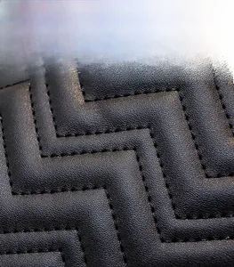Close-up of black quilted leather texture with durable zigzag stitching for backpack