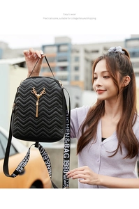 Close-up of black quilted mini backpack with wave stitching and gold deer pendant detail