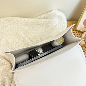 Quilted white shoulder bag interior showing capacity for phone, earbuds and lipstick