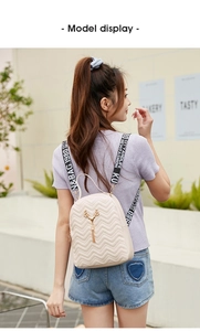 Outdoor back view of a beige quilted mini backpack with deer charm and woven straps