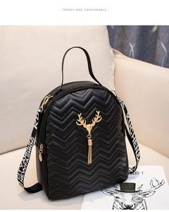 Detail of black mini backpack featuring chevron quilting, golden deer head and tassel