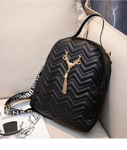 Close-up of black quilted mini backpack with golden deer charm and patterned strap