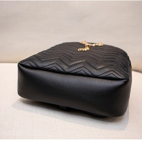 Close-up of black leather backpack featuring elegant V-shaped quilting and gold metal hardware