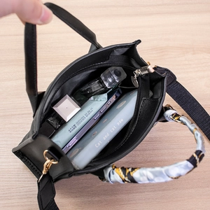 Quilted black handbag with scarf-wrapped handle showing interior capacity on wooden table