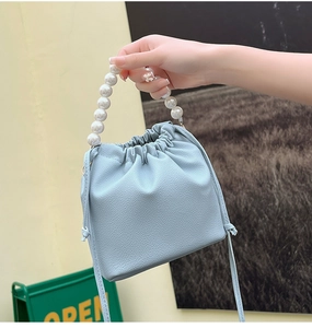 Detail view of light blue lychee pattern bucket bag with white pearl beaded handle strap