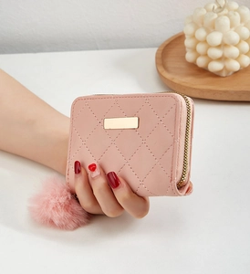 Détail du portefeuille rose en similicuir matelassé avec fermeture éclair dorée en main
