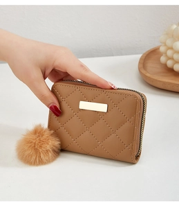 Détail du petit sac matelassé kaki avec plaque en métal doré et pompon en fourrure douce