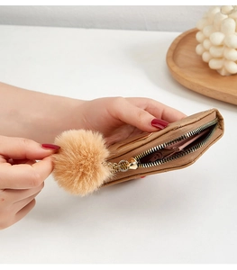Gros plan du petit porte-monnaie matelassé kaki avec fermeture éclair dorée et pompon doux