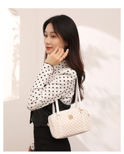 Vista laterale di una donna con borsa a tracolla monogramma elegante e dettagli dorati