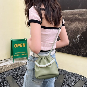 Chic light green lychee textured bucket bag with elegant white pearl handle and drawstring