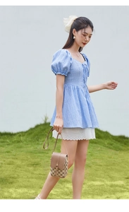 Détail d'un haut bleu clair à manches bouffantes avec texture quadrillée et lacets