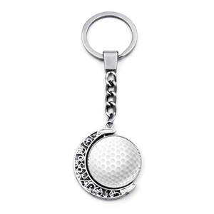 Detail of silver golf ball keychain with rotating pendant and ornate hollow pattern
