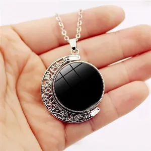 Rotating crescent moon necklace with intricate silver engraving and black spinning center