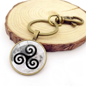 Bronze keychain with Triskelion moon glass pendant and lobster clasp on wood base