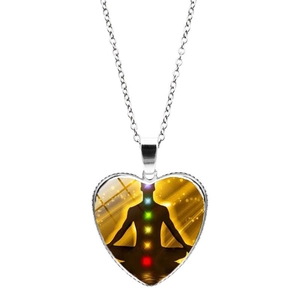 Vue détaillée du pendentif cœur argenté avec symbole de méditation sept chakras sur blanc