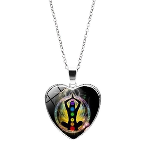 Détail du collier cœur argenté avec pose de yoga et symboles de chakra colorés sur verre