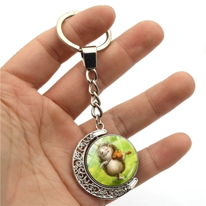 Macro detail of moon pendant keychain featuring a hedgehog playing violin on glass