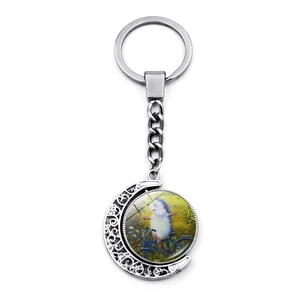 Close-up of a silver crescent moon keychain with an illustration of a hedgehog on a bicycle