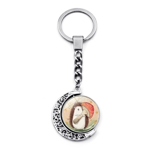 Rotating silver metal keychain detail showing a hedgehog holding a mushroom illustration