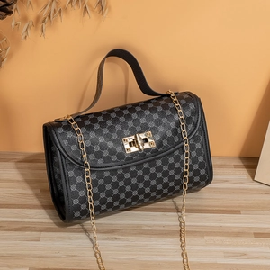 Detail of black embroidered crossbody bag with gold chain and floral patterns on wood desk