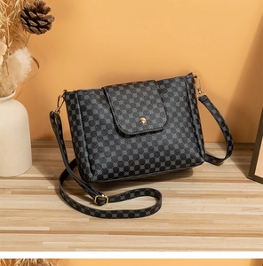 Detail of grey bucket bag with black geometric patterns and gold magnetic closure
