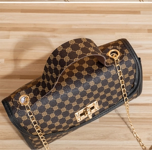 Detail view of brown chain bag featuring gold clover prints and metal twist lock