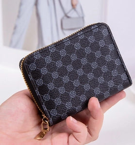 Macro view of a mini black coin purse with geometric print and golden zipper detail